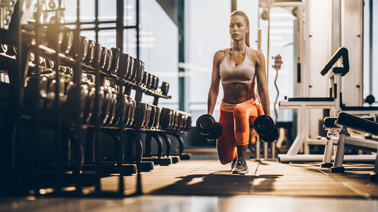 woman doing a weighted lunge in a HIIT workout plan