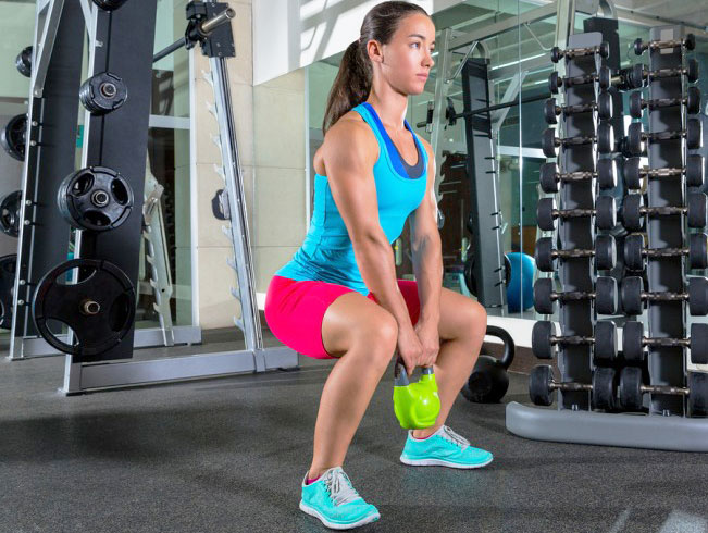 woman doing a sumo squat with a kettlebell 