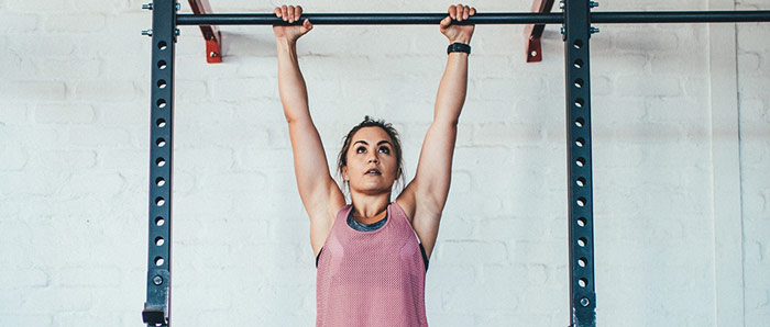 woman hangs from pull up bar