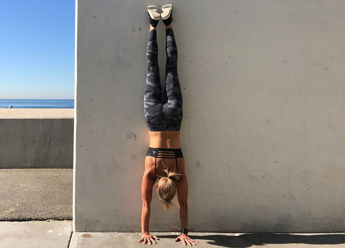 woman performs wall walk hand stand