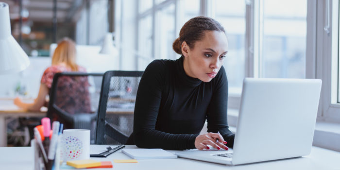 Young woman using a laptop, sat at a desk.