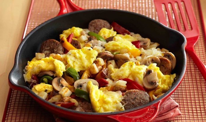 a skillet of chicken sausages, eggs and veg 