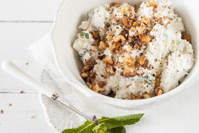 A bowl of cottage cheese with walnuts and honey on top