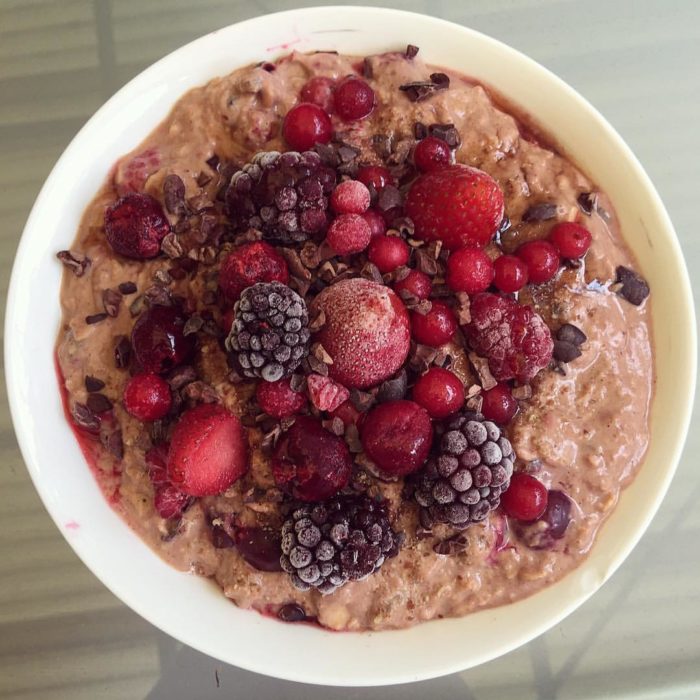 A bowl of protein and oats topped with frozen red berries
