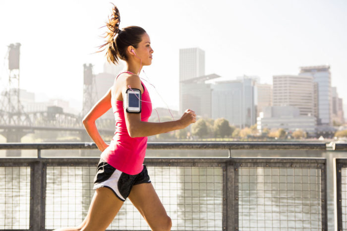 woman doing a cardio workout of running along a river in a city settting 