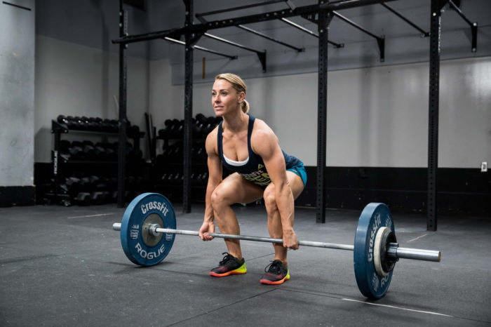 Woman about to perform a deadlift with a weighted barbell