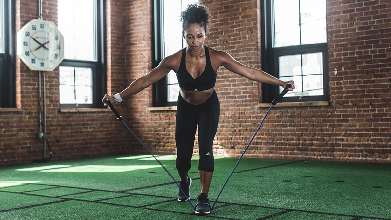 Fit, strong and athletic woman performing workout with resistance band in gym studio