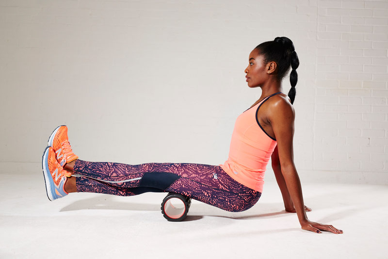 fit and healthy female foam rolling hamstring muscles