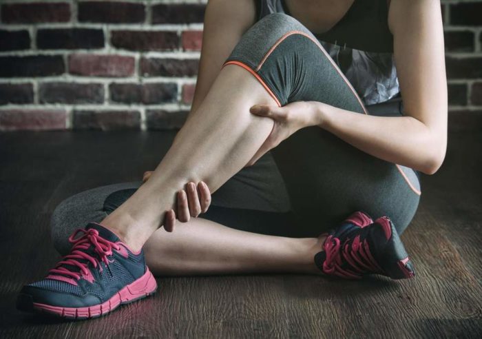 Woman in the gym clutching her injured calf