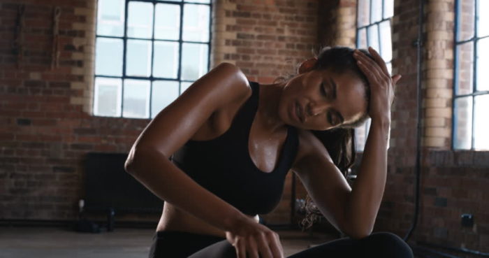 Woman in the gym looking tired and frustrated at lack of results after a workout