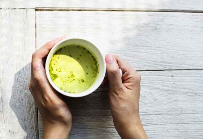 someone holding a cup of matcha tea